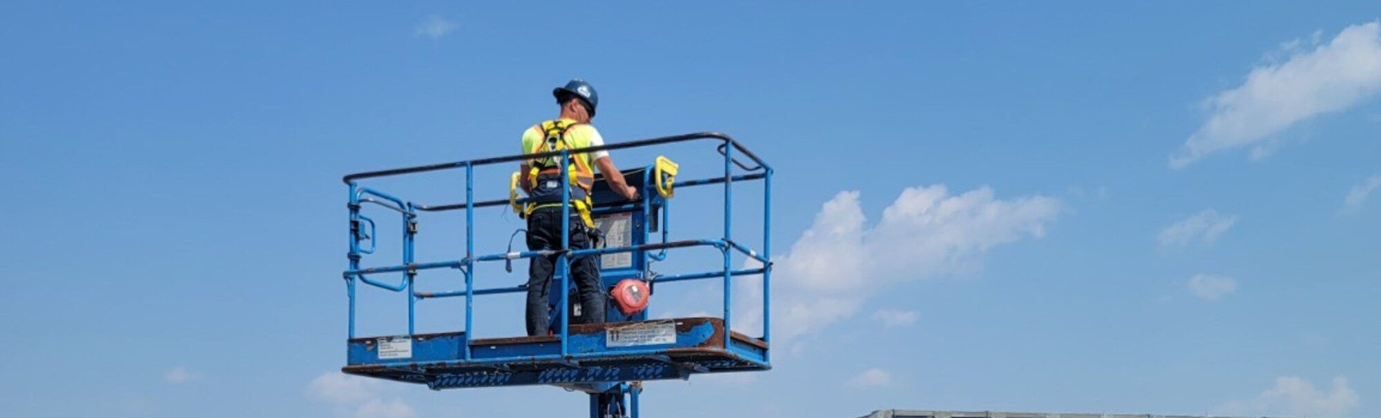 Operator working from the raised basket of a boom lift at a Manitoba worksite during on-site boom lift training