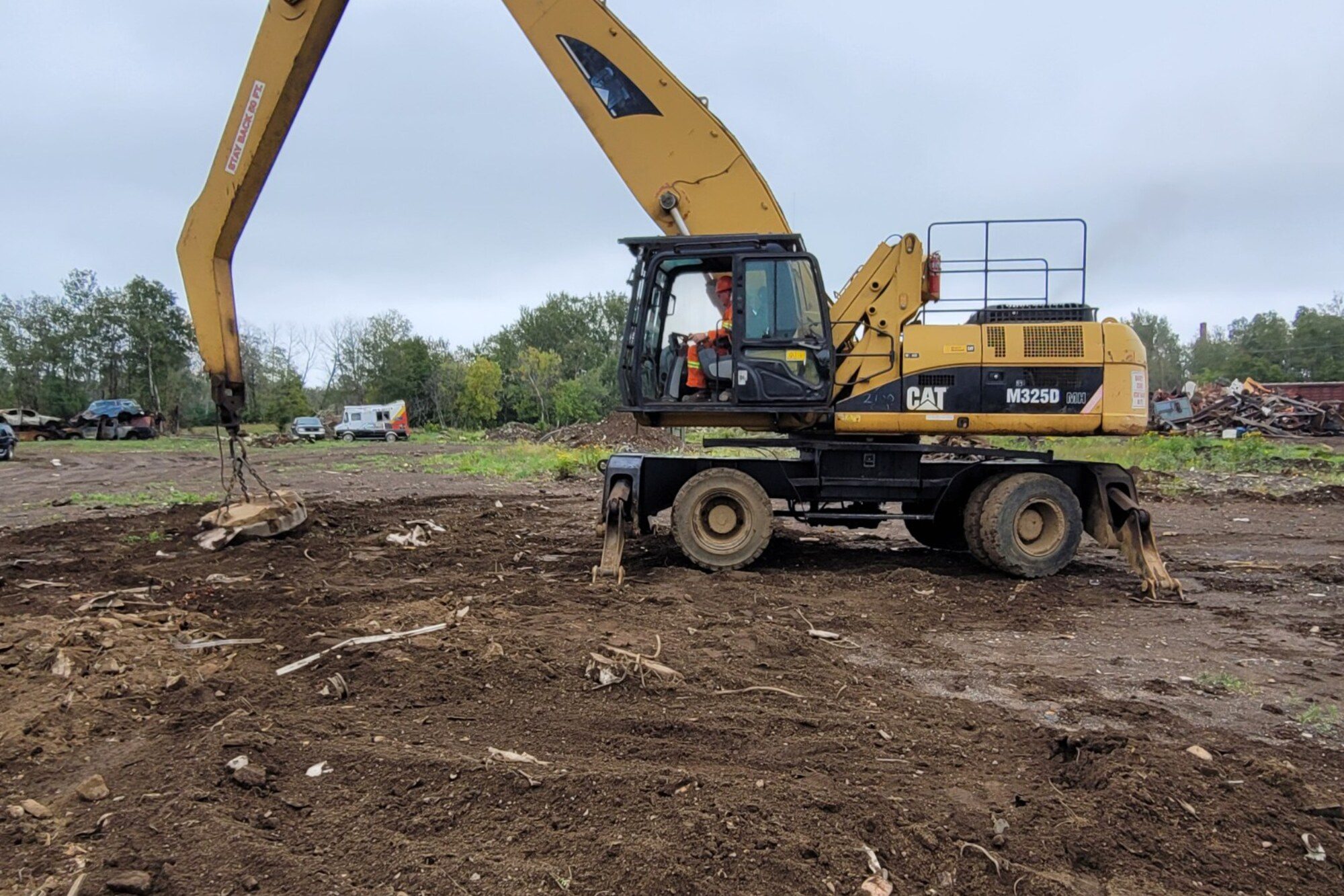 Operator working a wheeled excavator on cleared ground at a Manitoba site during on-site excavator training