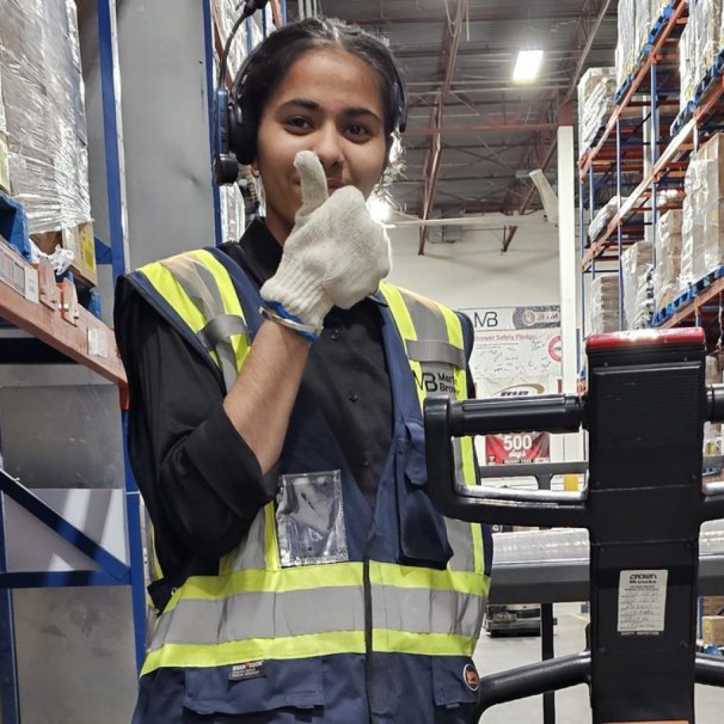 Warehouse worker in a hi-vis vest standing with an electric pallet jack during on-site pallet jack operator training in Winnipeg