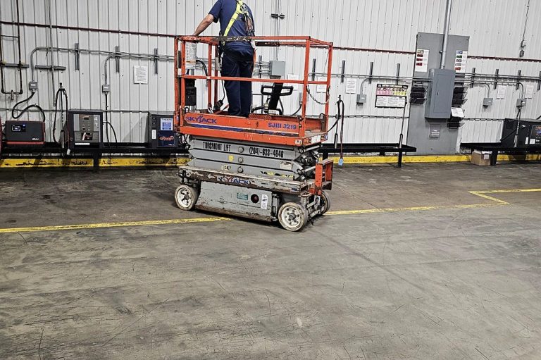 Worker on a raised scissor lift platform inside a building during on-site scissor lift training in Winnipeg