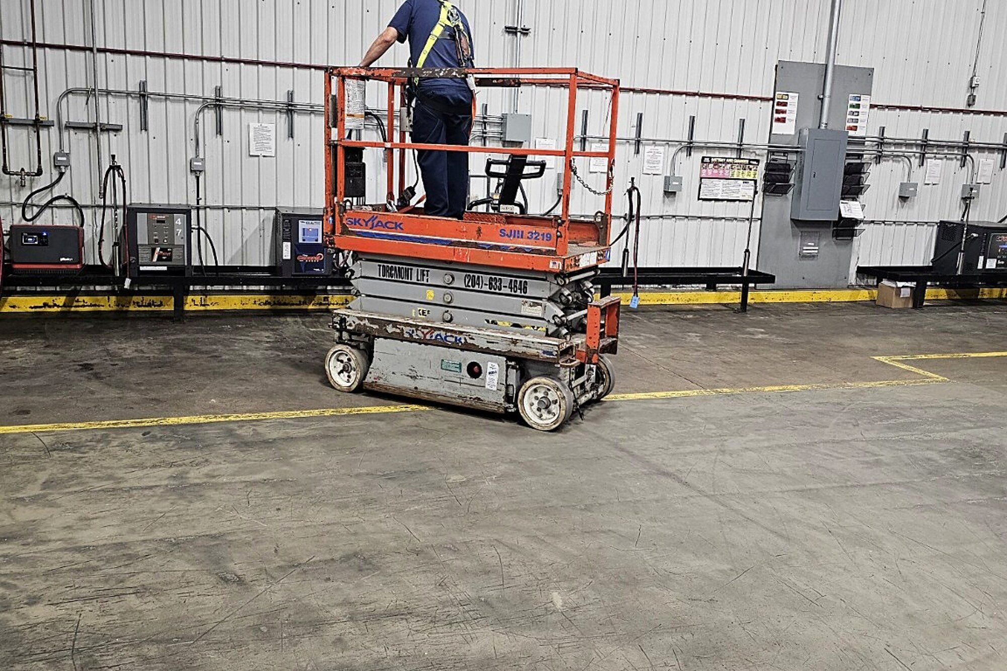 Worker on a raised scissor lift platform inside a building during on-site scissor lift training in Winnipeg