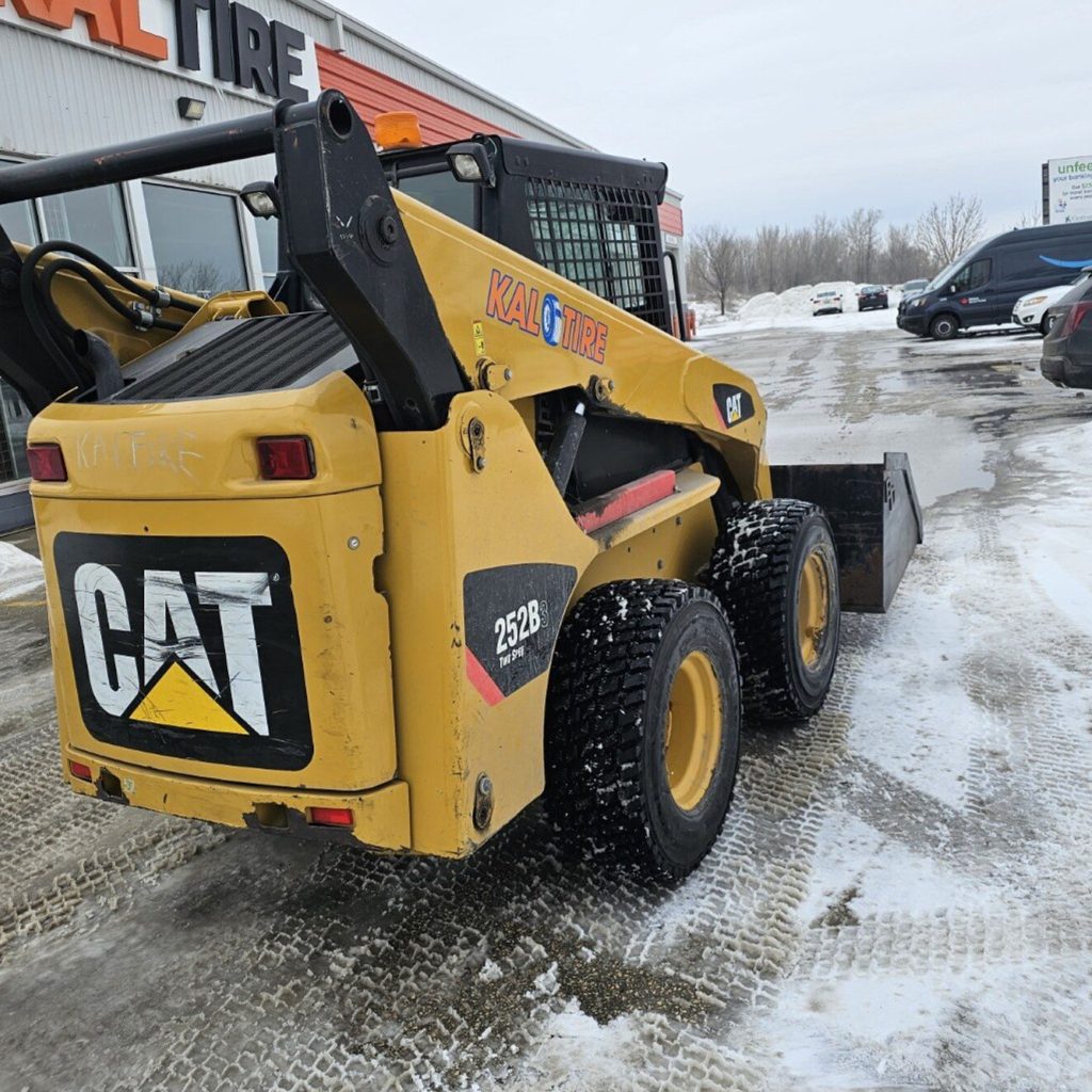 Skid steer loader clearing snow outside a Winnipeg building during on-site skid steer operator training