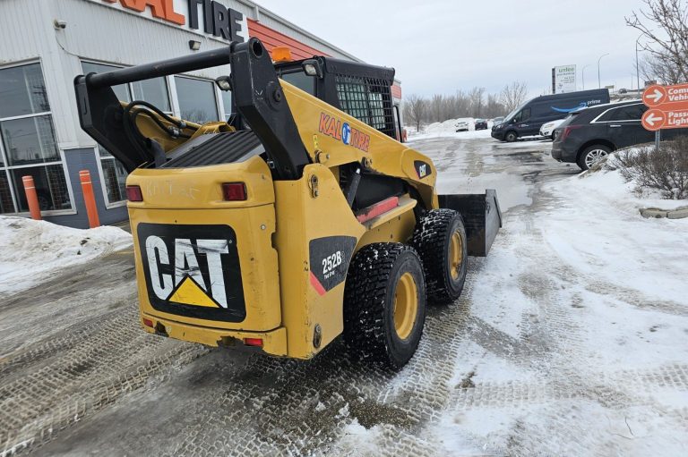 Skid steer loader clearing snow outside a Winnipeg building during on-site skid steer operator training