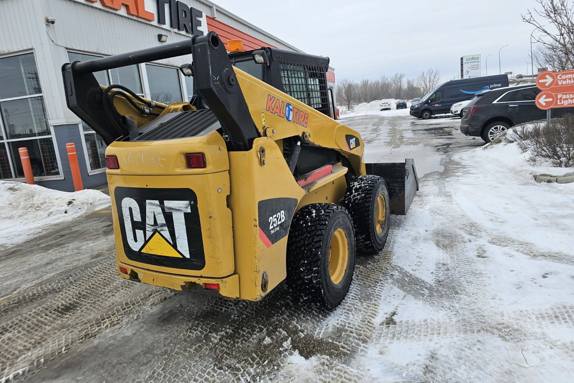 Skid steer loader clearing snow outside a Winnipeg building during on-site skid steer operator training